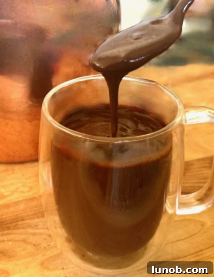 A rich, thick Italian hot chocolate (cioccolata calda) in a mug, garnished with whipped cream and chocolate shavings.