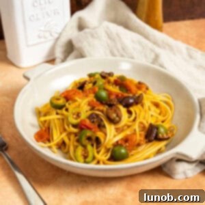 Linguine puttanesca topped with olives and capers in a bowl.