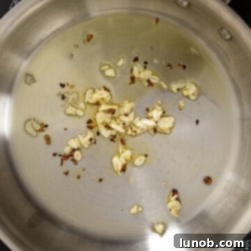 Garlic and crushed red pepper sauteing in a pan, releasing their aromas.