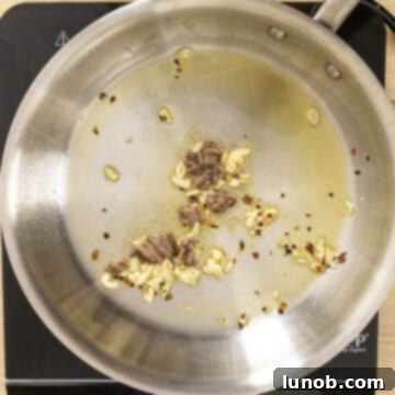 Chopped anchovies combined with garlic in a pan, dissolving into the oil.