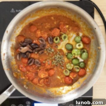 Olives and capers stirred into the simmering puttanesca sauce.