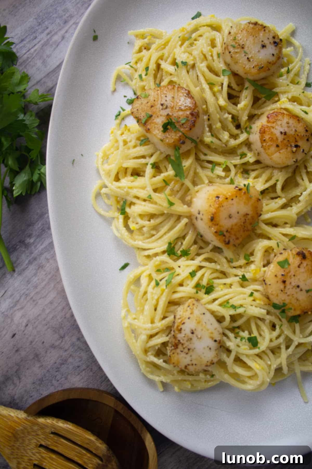 lemon pesto spaghetti with scallops and garnished with fresh chopped parsley