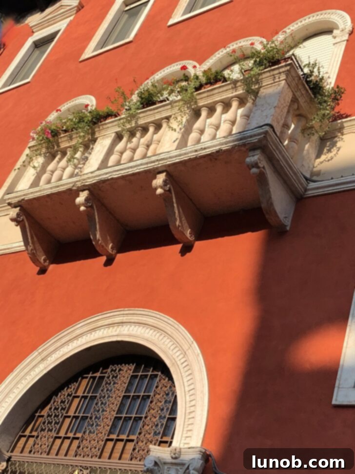 Verona, Italy street with buildings in shades of yellow, peach, and green with tiny plant-filled balconies