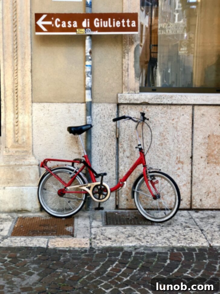 Sign pointing to Juliet's House in Verona, with a charming red bicycle