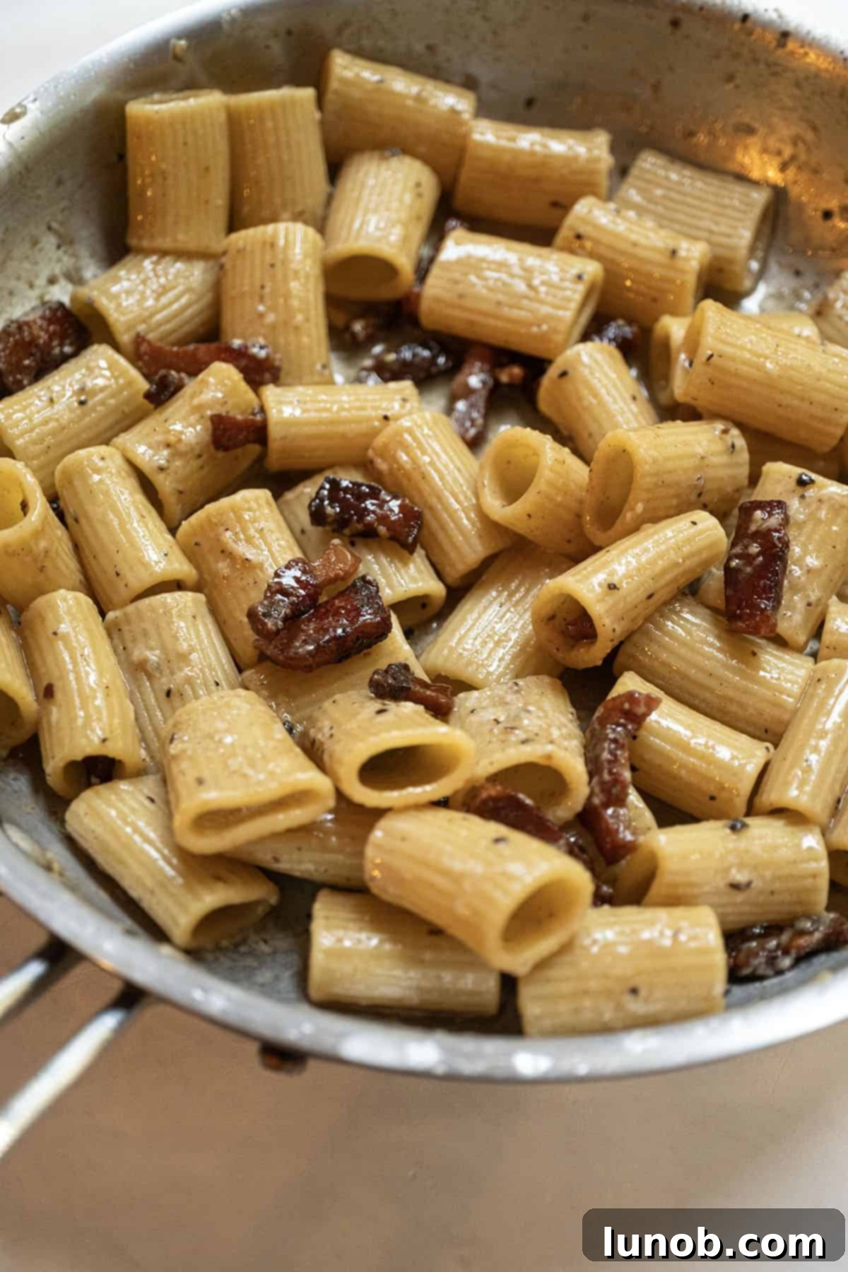 Pasta Alla Gricia: Rome's Simple Perfection 12 The finished Pasta alla Gricia, with a creamy sauce and crispy guanciale, ready to be served from the pan.