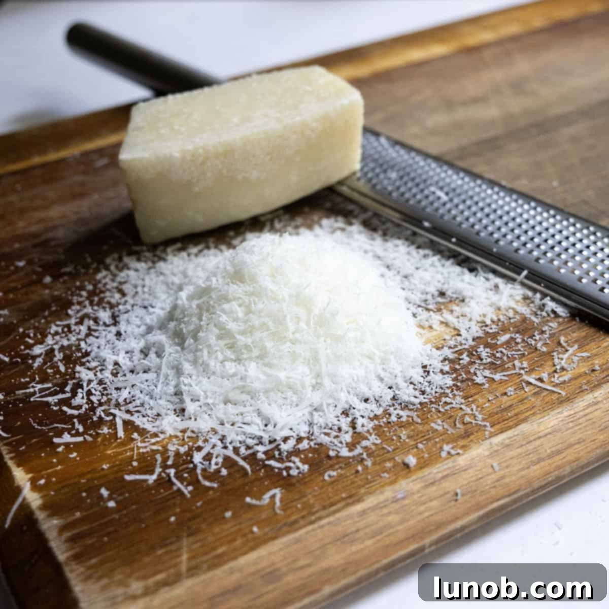 Pasta Alla Gricia: Rome's Simple Perfection 5 A mound of finely grated Pecorino Romano cheese on a cutting board, prepared for the pasta dish.