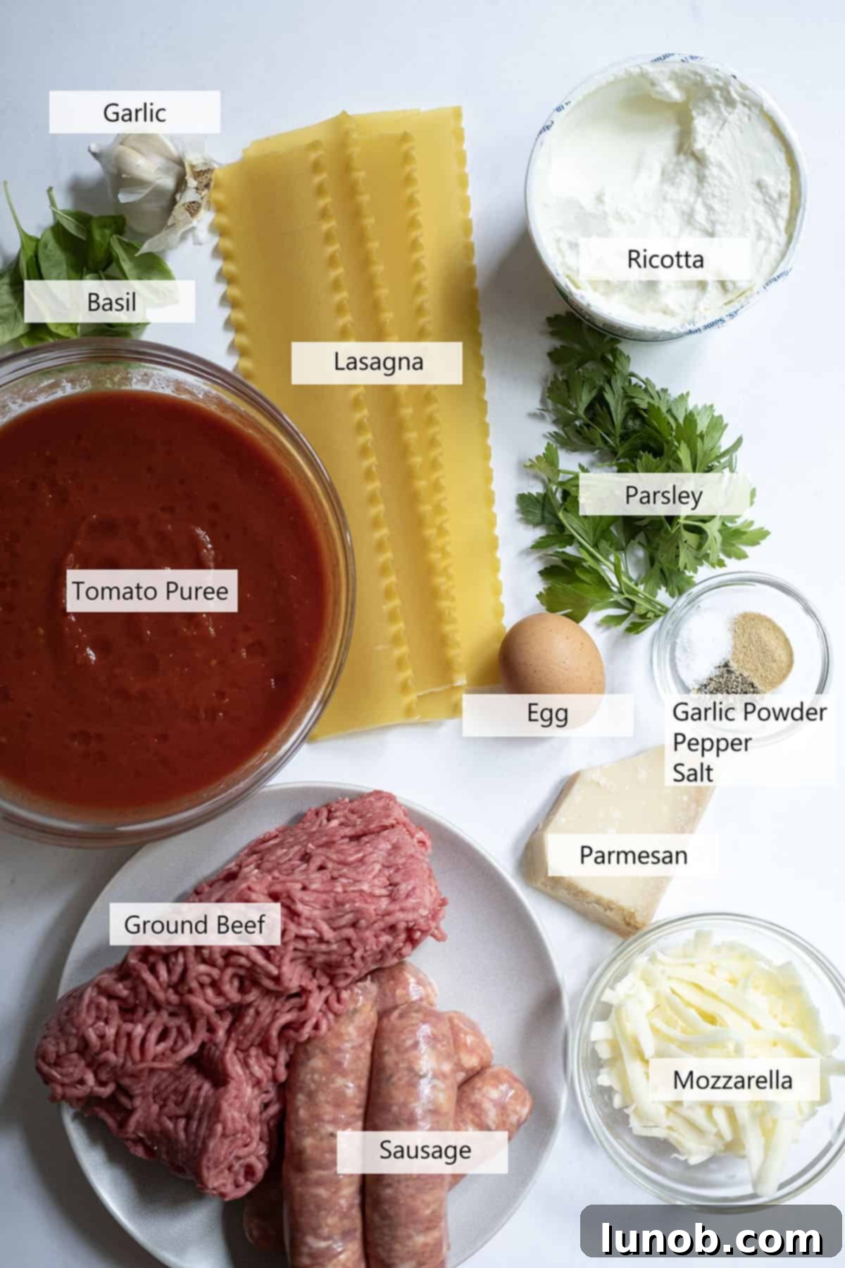 A selection of fresh ingredients laid out for making lasagna, including ground meat, ricotta cheese, tomatoes, and herbs.