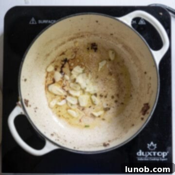 Minced garlic cloves sauteing in olive oil in a Dutch oven.