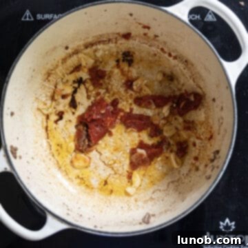 Tomato paste caramelizing, stirring into the garlic and olive oil in the Dutch oven.