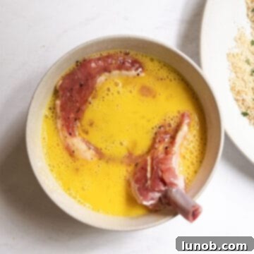 Golden Crispy Milanese Pork Chop 5 Pork chop in bowl of whisked egg.