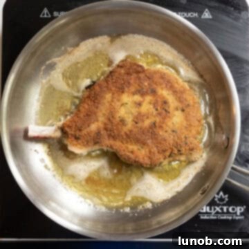 Golden Crispy Milanese Pork Chop 8 Pork chop flipped over in frying pan with golden brown coating.