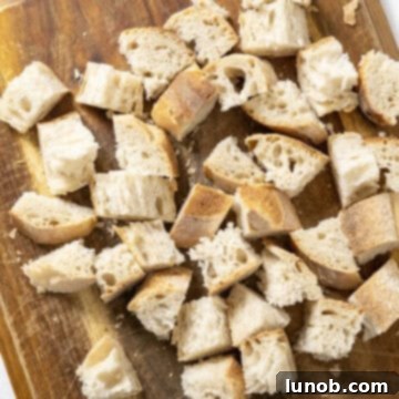 Crispy Homemade Parmesan Croutons 4 Chopped up bread on a cutting board.