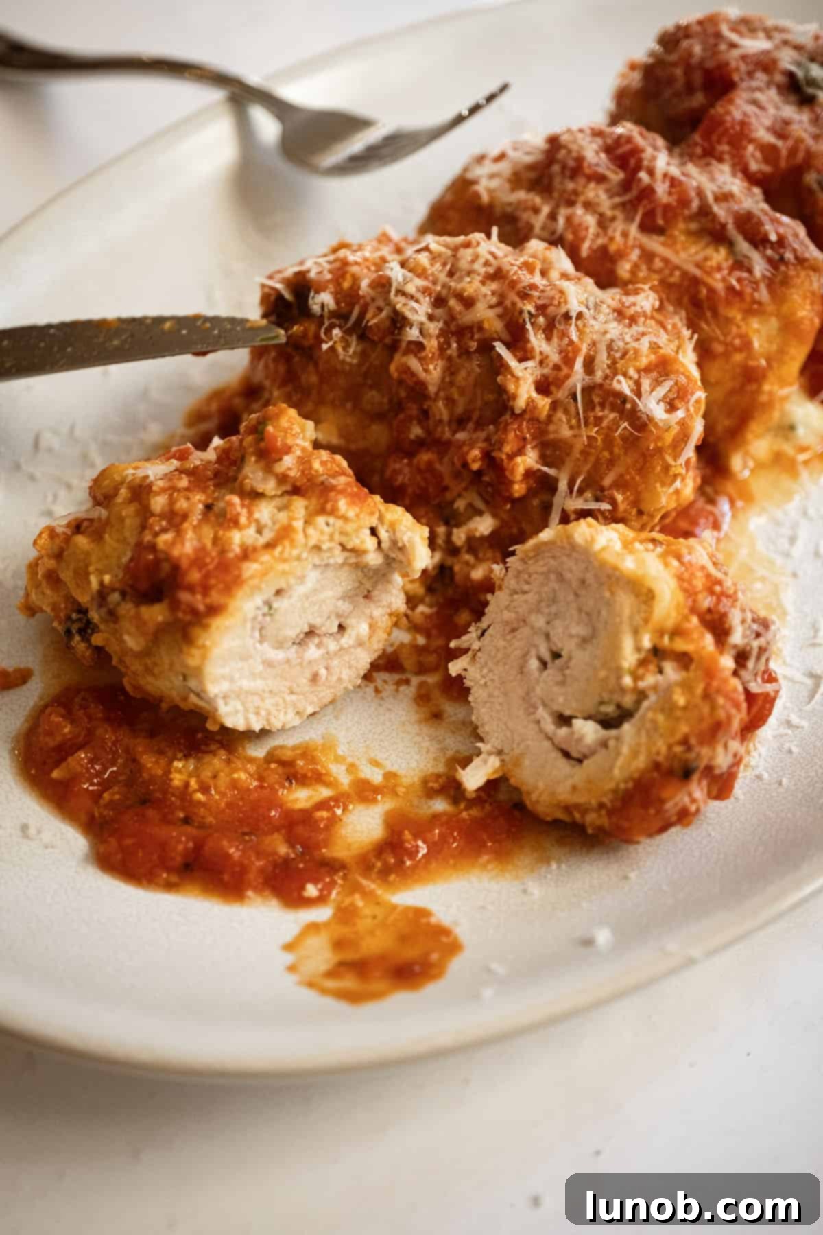 Chicken rollatini cut open with ricotta filling inside, revealing the creamy and savory interior.