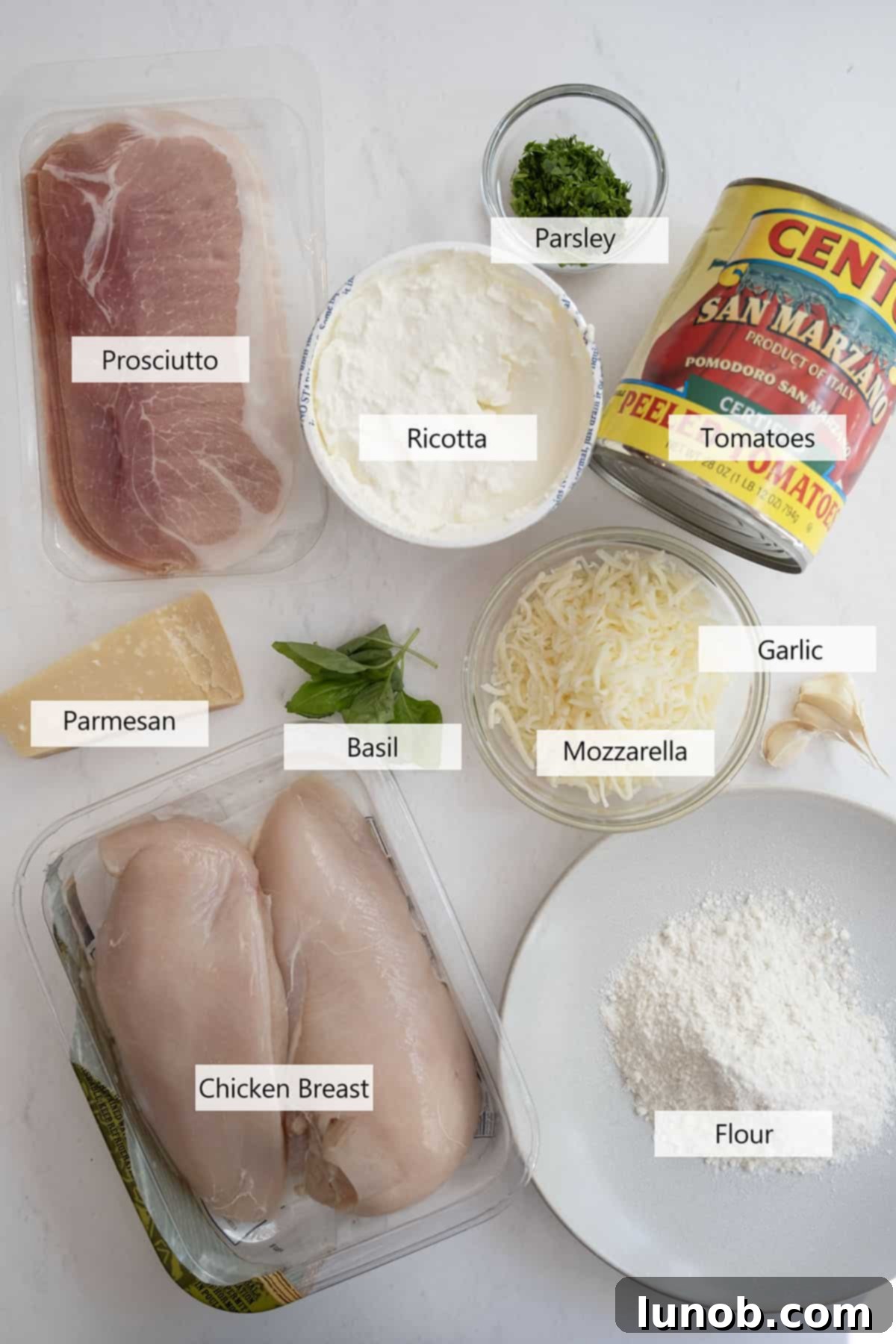 A selection of fresh ingredients laid out for the Chicken Rollatini recipe, including chicken breasts, prosciutto, ricotta, and tomatoes.