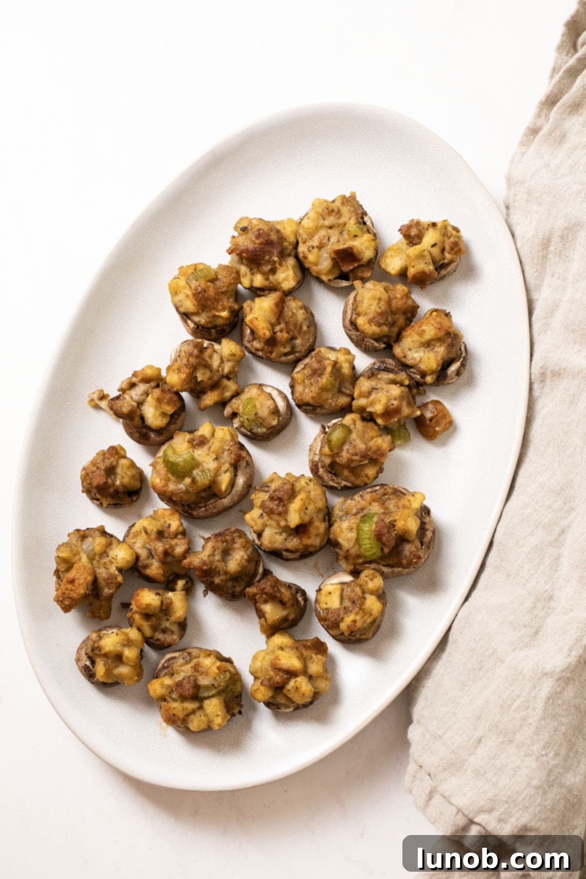 Ultimate Italian Sausage Stuffed Mushrooms 11 Close-up of baked Italian Sausage Stuffed Mushrooms on a plate, garnished with fresh parsley.