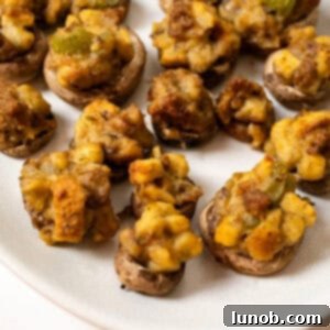 Ultimate Italian Sausage Stuffed Mushrooms 12 Italian Sausage Stuffed Mushrooms on a plate, garnished with fresh herbs.