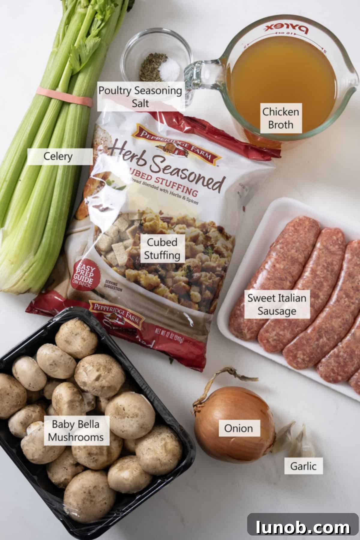 Ultimate Italian Sausage Stuffed Mushrooms 3 Fresh ingredients for Italian Sausage Stuffed Mushrooms arranged on a wooden board, including mushrooms, sausage, celery, onion, and spices.