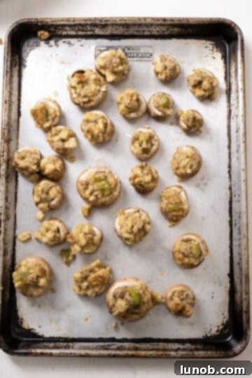 Ultimate Italian Sausage Stuffed Mushrooms 9 Mushrooms meticulously stuffed with the sausage mixture and arranged on a baking sheet.