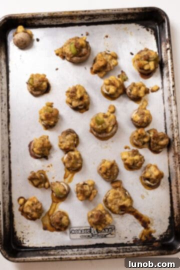 Ultimate Italian Sausage Stuffed Mushrooms 10 Golden-brown, baked stuffed mushrooms fresh out of the oven on a baking sheet.
