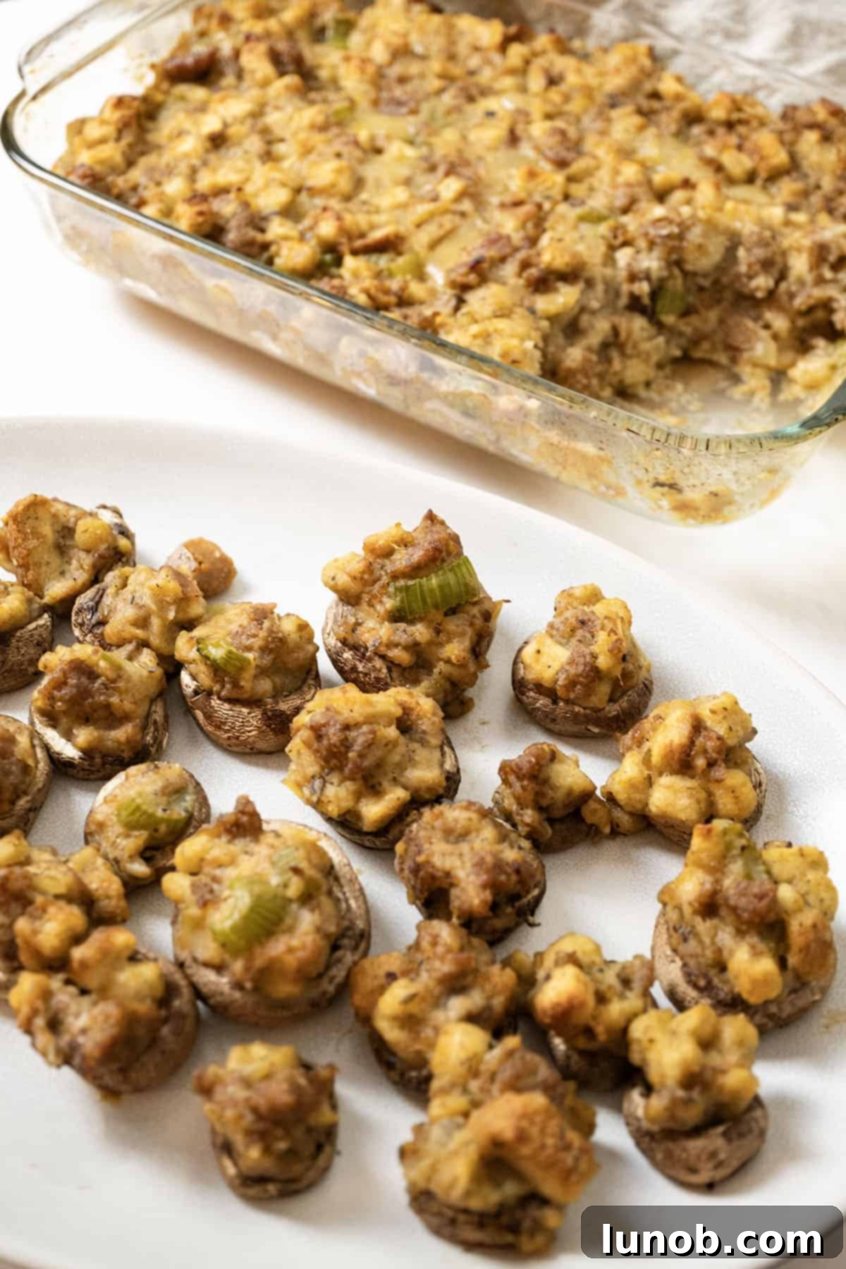 Savory Italian Sausage Thanksgiving Stuffing 3 Italian sausage stuffing baked in a glass baking pan, ready to serve with a side of stuffed mushrooms.