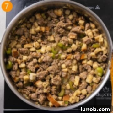 Savory Italian Sausage Thanksgiving Stuffing 8 Chicken broth being poured over stuffing cubes in a saucepan, initiating the absorption process.
