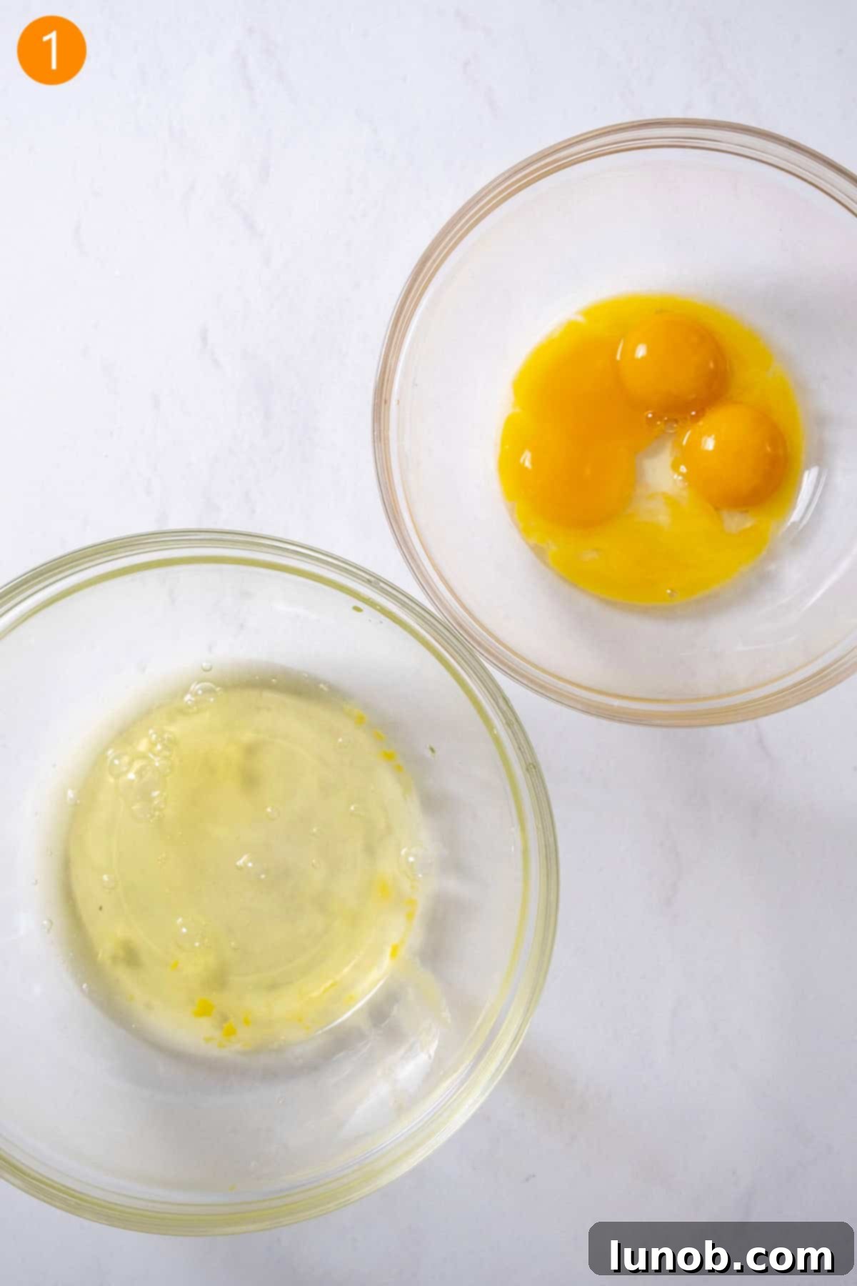 Egg yolks and egg whites carefully separated into two distinct bowls.