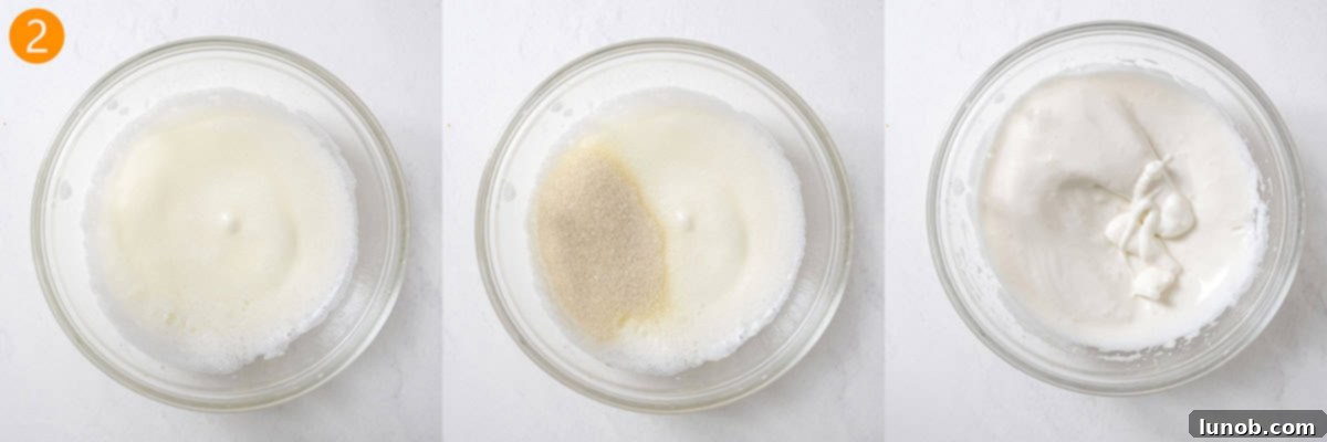 A hand mixer beating egg whites with sugar until they reach stiff peaks, showing the glossy, firm texture.