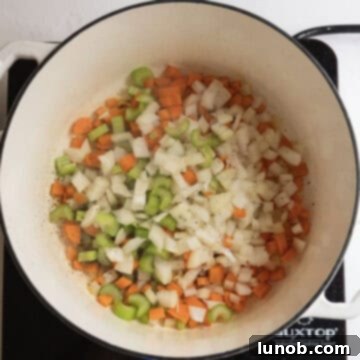 Comforting Chicken Tortellini Soup 6 Chopped carrots, celery, and onion sautéing in a pot with olive oil.