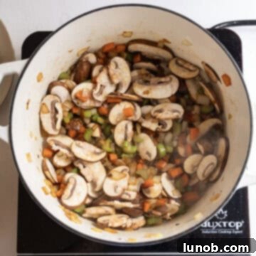 Comforting Chicken Tortellini Soup 8 Sliced mushrooms sautéing with the seasoned vegetables in the pot.