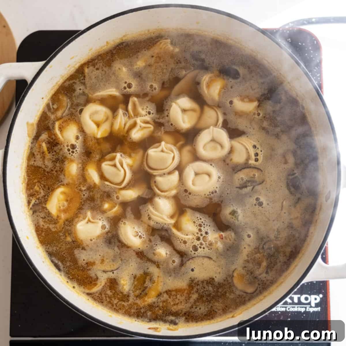 Comforting Chicken Tortellini Soup 10 The chicken tortellini soup simmering in the pot, with tortellini just added and floating on top.