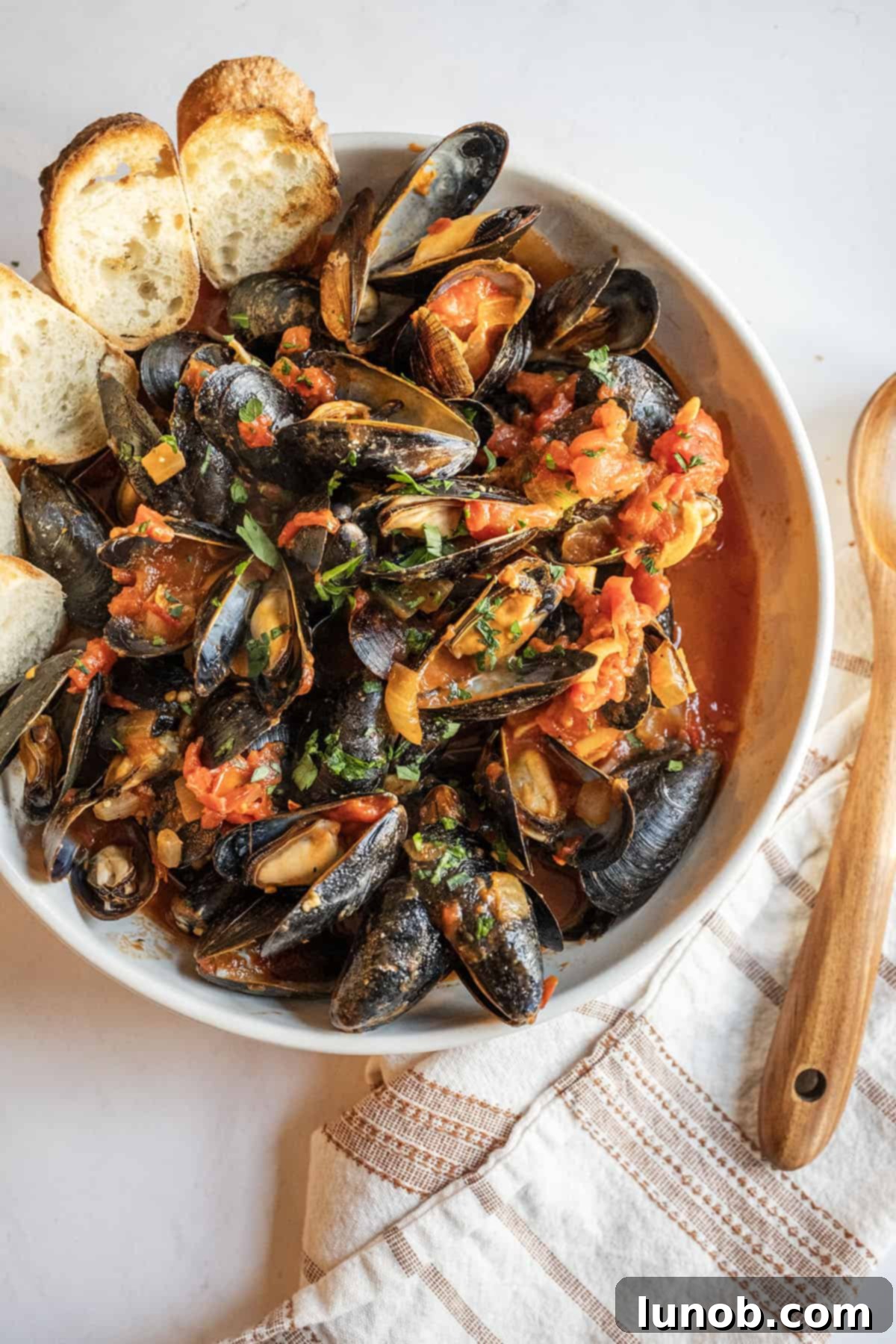 Mussels Fra Diavolo in a serving bowl with crostini.