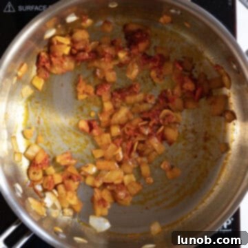 Onions sauteing with garlic, tomato paste, and calabrian chili peppers in a pan.