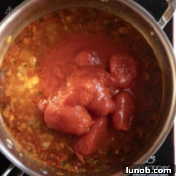Whole plum tomatoes added to the wine filled pan.
