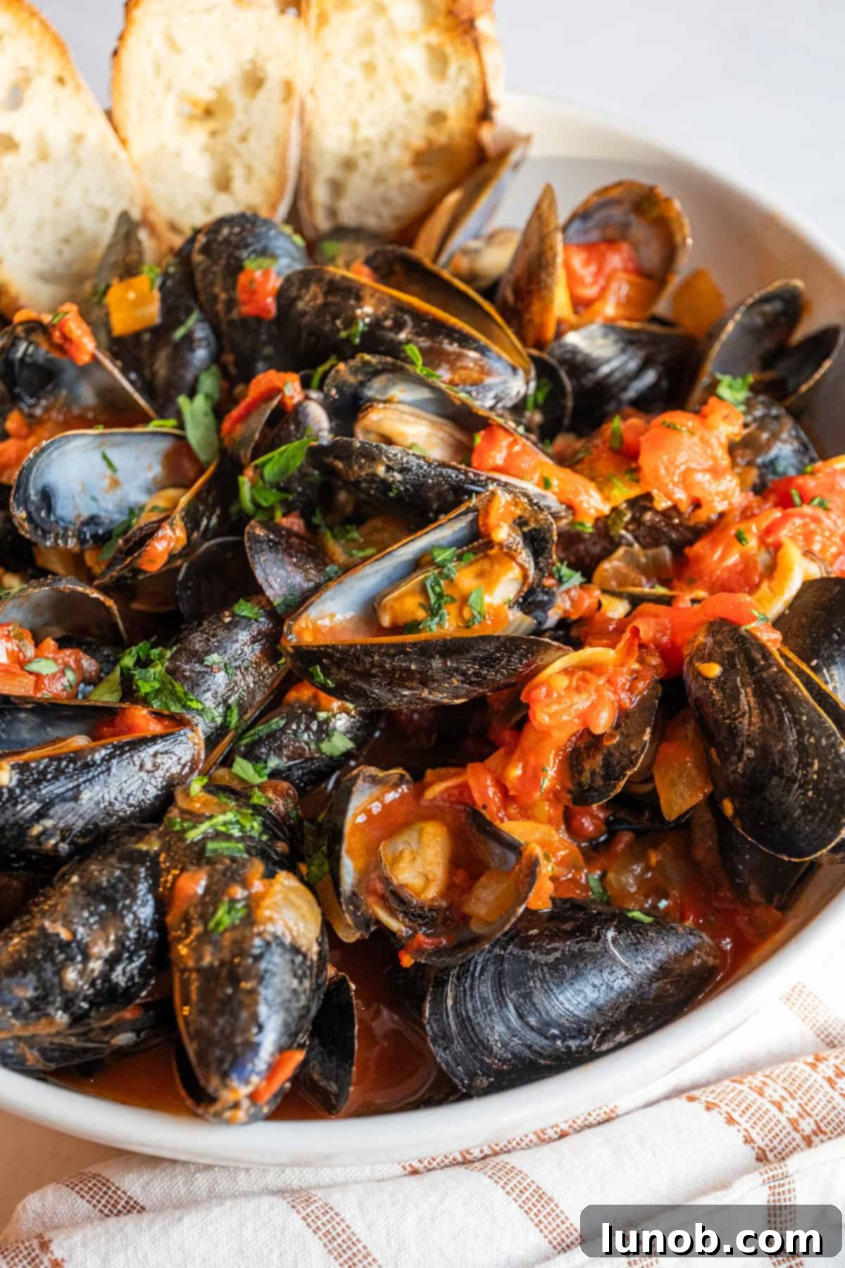 Mussels Fra Diavolo in a serving bowl with crostini.