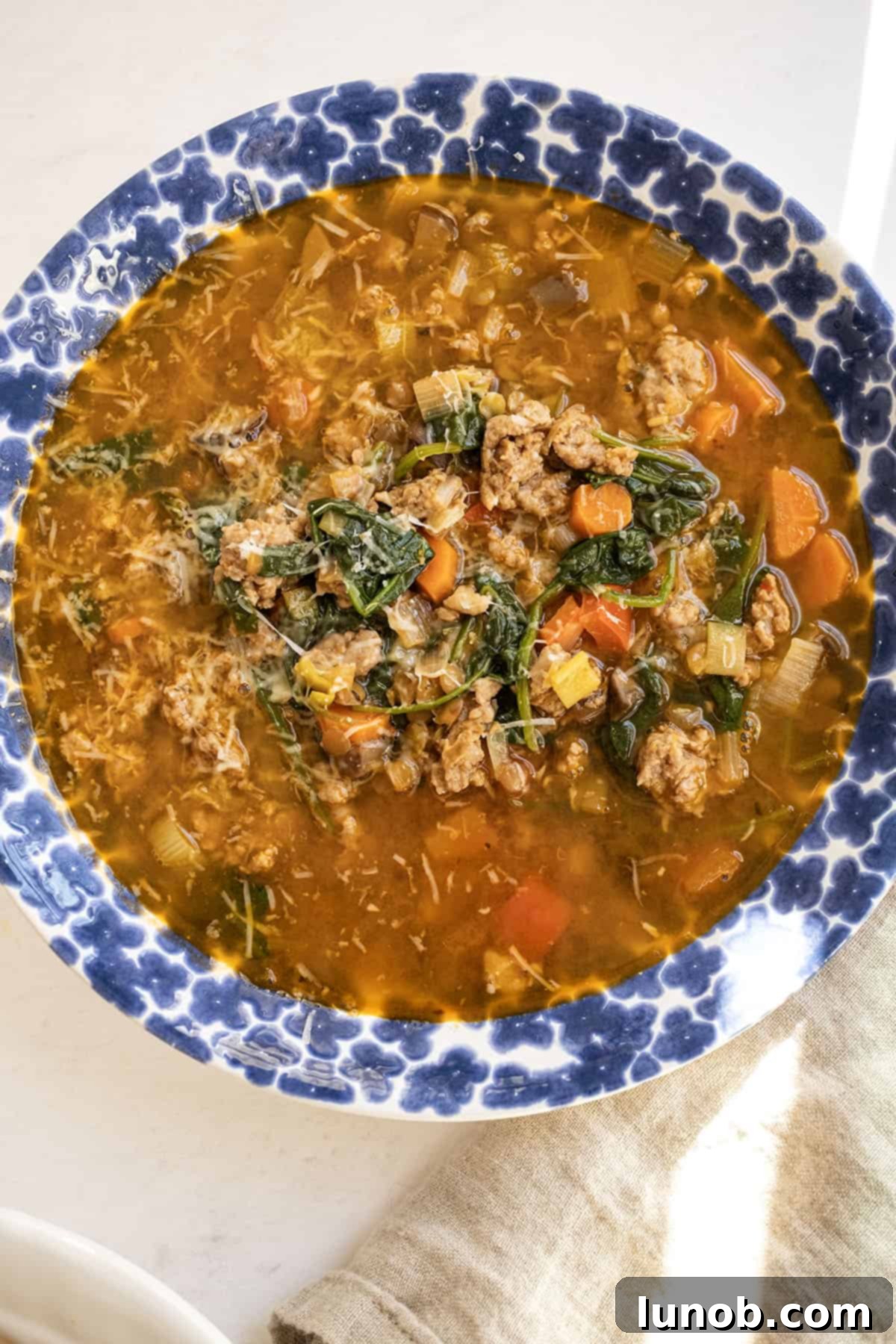 Soul-Warming Sausage and Lentil Soup 10 A close-up shot of a steaming bowl of Italian sausage and lentil soup, highlighting the rich broth, tender lentils, and flavorful sausage, ready to be enjoyed.