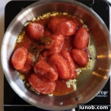 Whole plum tomatoes added to sauteed olive oil.