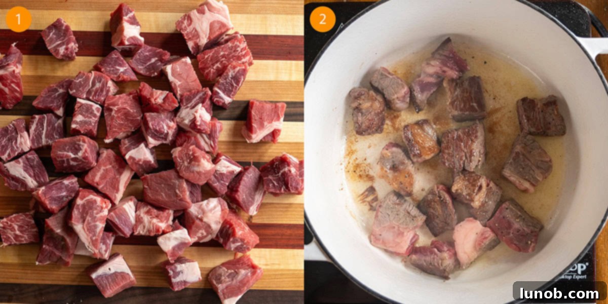 Close-up of 1-inch chunks of seasoned beef chuck roast searing to a golden brown in a cast iron dutch oven.