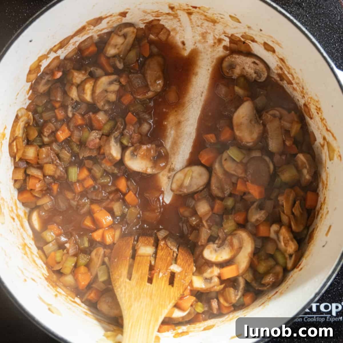 A visual guide showing red wine reduced by half in a pot, demonstrating the correct consistency.