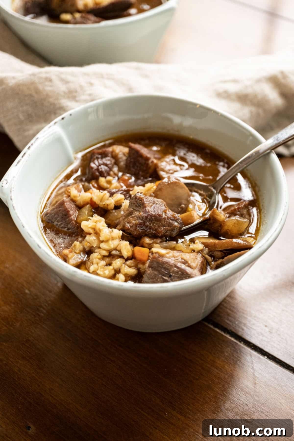 A rustic bowl of beef and barley soup, garnished with fresh herbs, ready to be enjoyed.