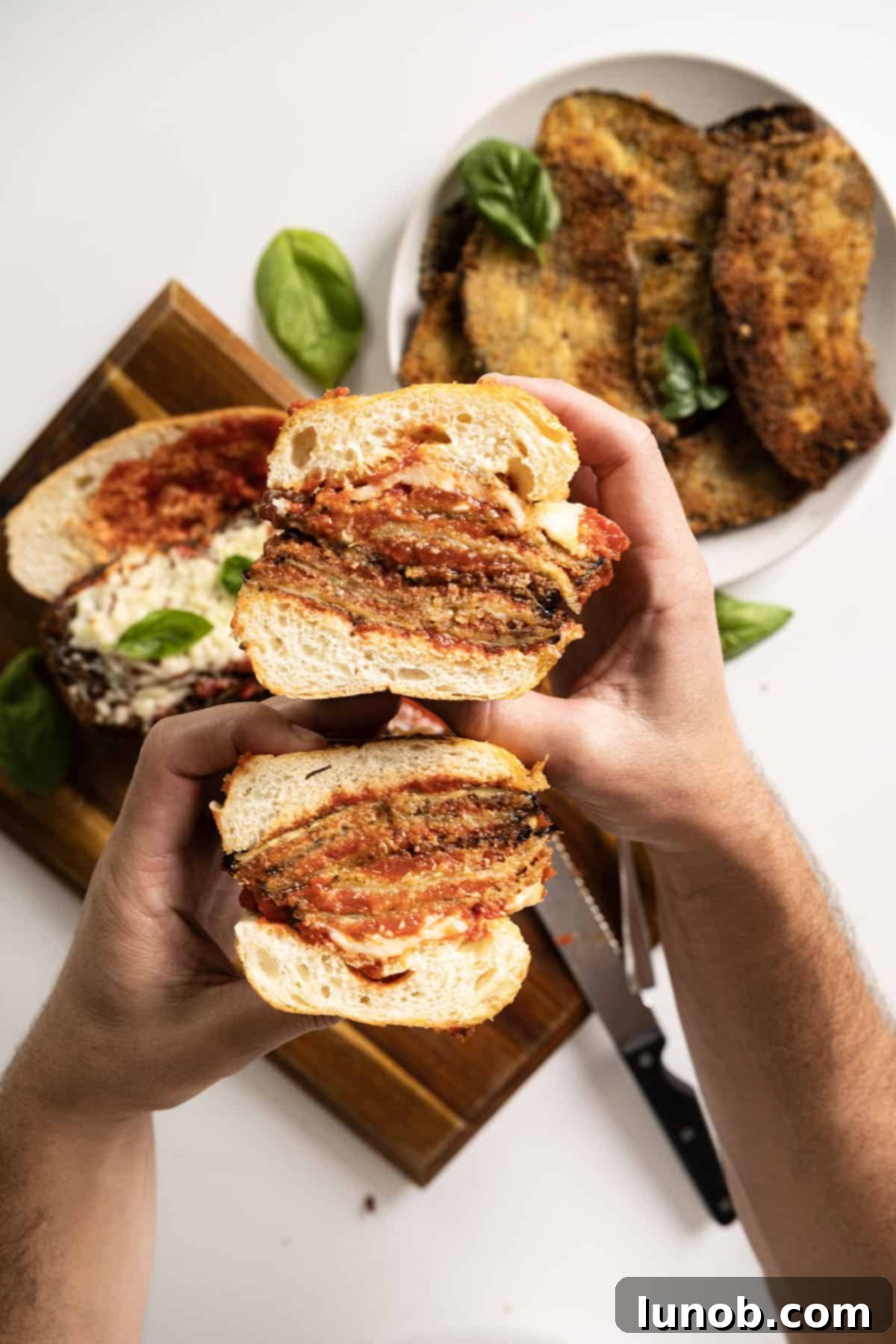 Holding an eggplant parm sandwich cut in half.