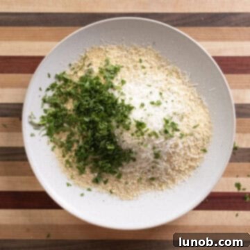 A plate of breadcrumbs, parsley, salt, parmesan, and garlic powder.