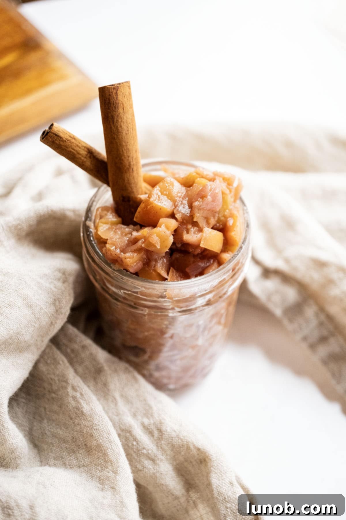 Golden Apple & Spice Chutney 2 Homemade spiced apple chutney in a mason jar, garnished with cinnamon sticks, ready to serve or store.