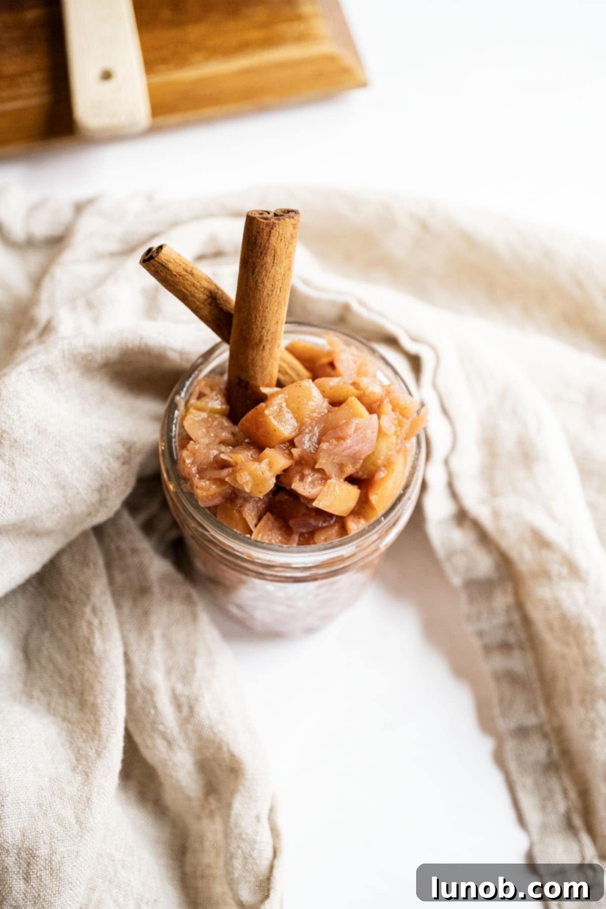 Golden Apple & Spice Chutney 10 A charming close-up of spiced apple chutney in a mason jar, elegantly garnished with a cinnamon stick and fresh mint.