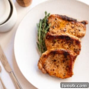 Ultimate Cast Iron Boneless Pork Chops 10 Boneless pork chops cooked on a plate with rosemary and thyme