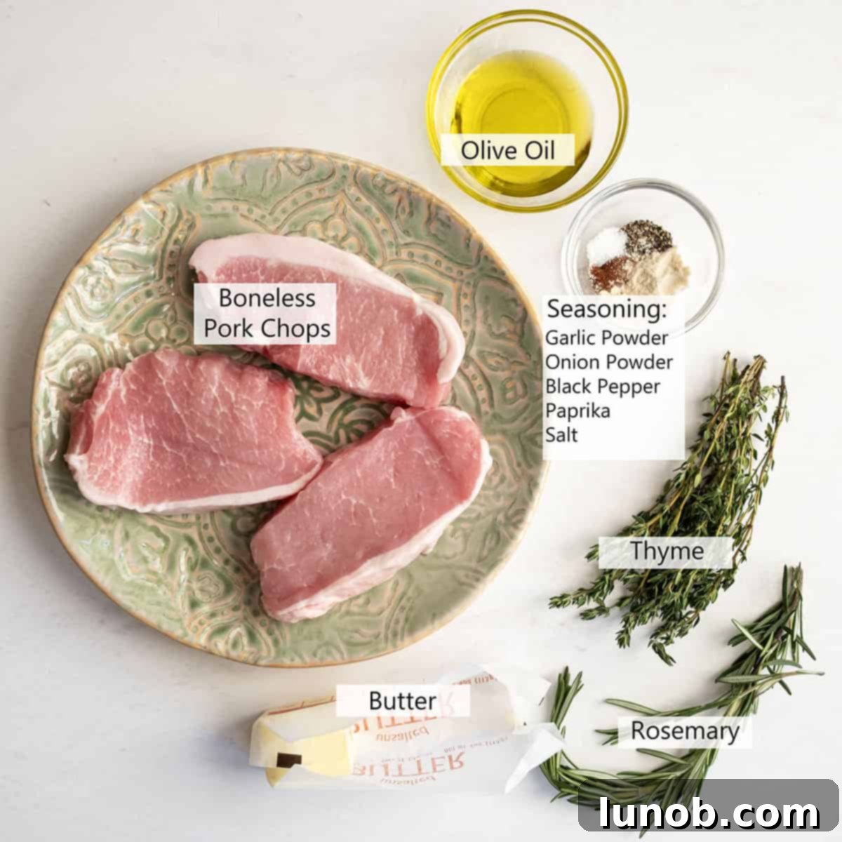 Ultimate Cast Iron Boneless Pork Chops 3 Fresh ingredients laid out for cooking: boneless pork chops, butter, rosemary, thyme, olive oil, and various spices.