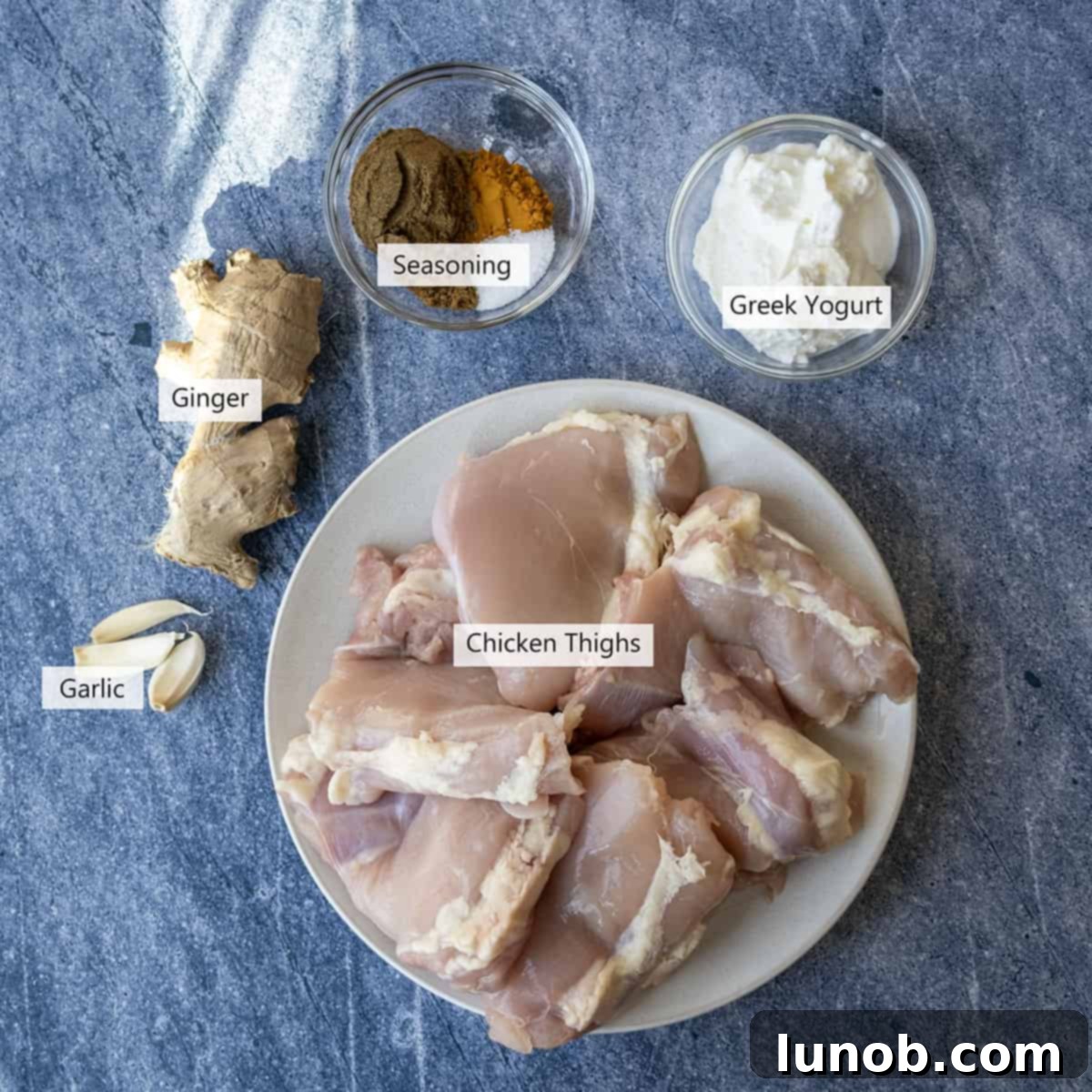 Velvet Butter Chicken Soup 3 Collection of fresh ingredients for marinating chicken thighs, including ginger, garlic, Greek yogurt, and spices.