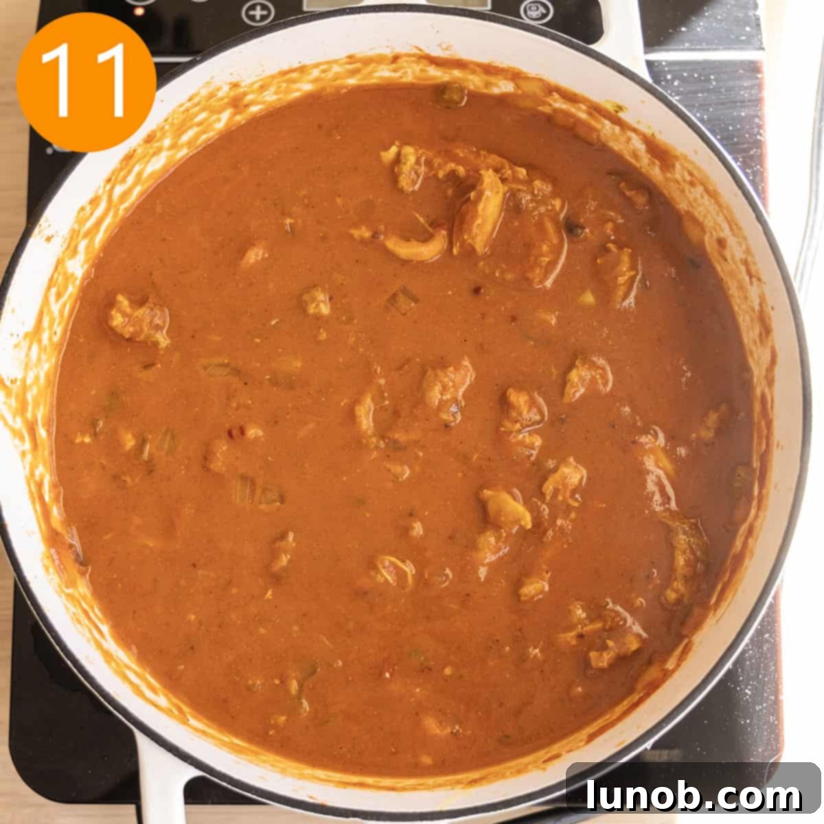 Velvet Butter Chicken Soup 10 A can of coconut milk being stirred into the finished butter chicken soup in a pot.