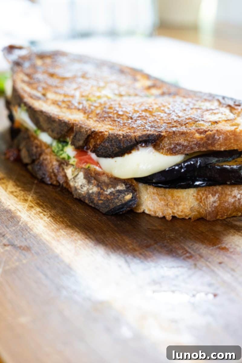Caprese Eggplant Melt 7 Close-up of a halved eggplant caprese grilled cheese, revealing melted cheese, roasted tomatoes, and grilled eggplant.