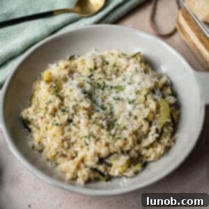 Zucchini risotto in a bowl topped with parmigiano and parsley.
