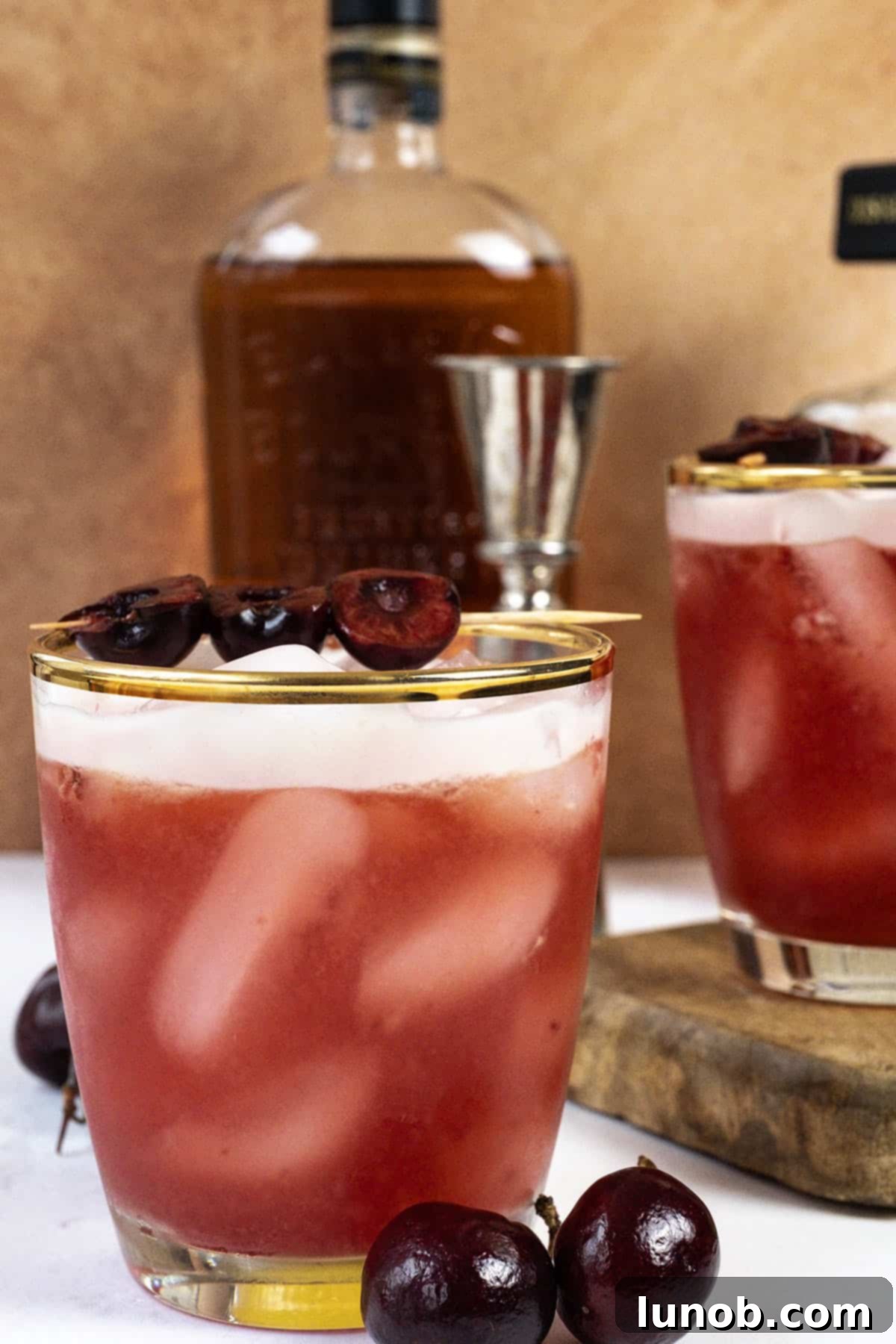 A perfectly prepared Cherry Amaretto Sour in a glass, with a frothy top and garnished with a fresh cherry.